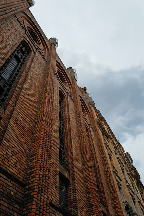 Free Upward view of a Gothic church with intricate brickwork and a moody sky. Stock Photo