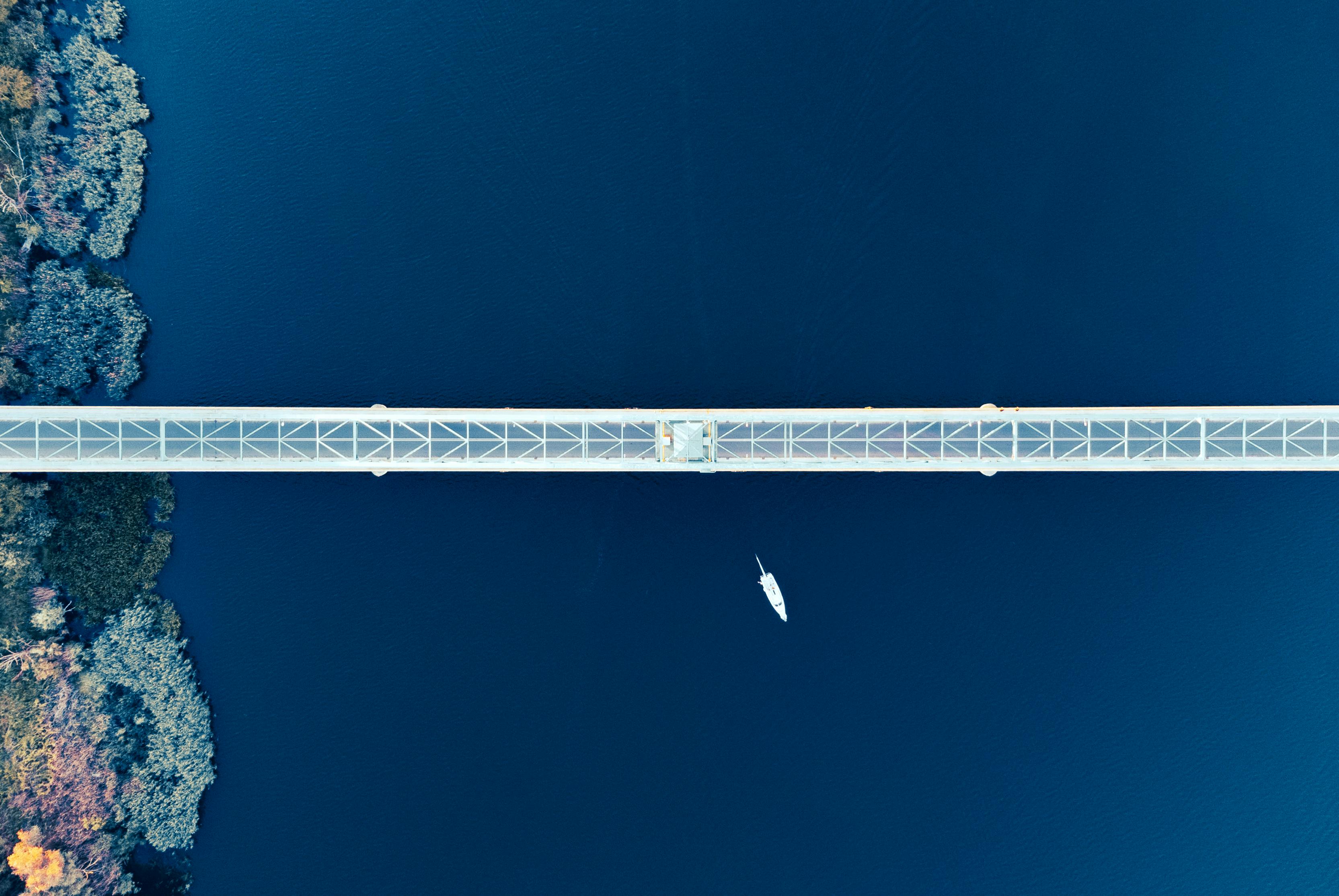 Stunning aerial view of a bridge crossing a serene waterbody in Gryfin, Poland, highlighting its geometric beauty.