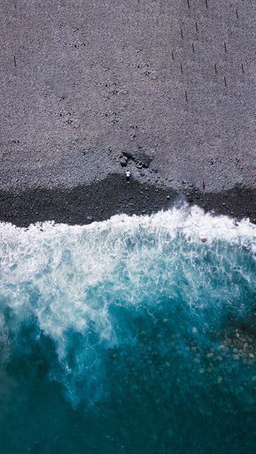 Stunning aerial view of rocky shorelines and azure ocean waves in Madeira, Portugal.