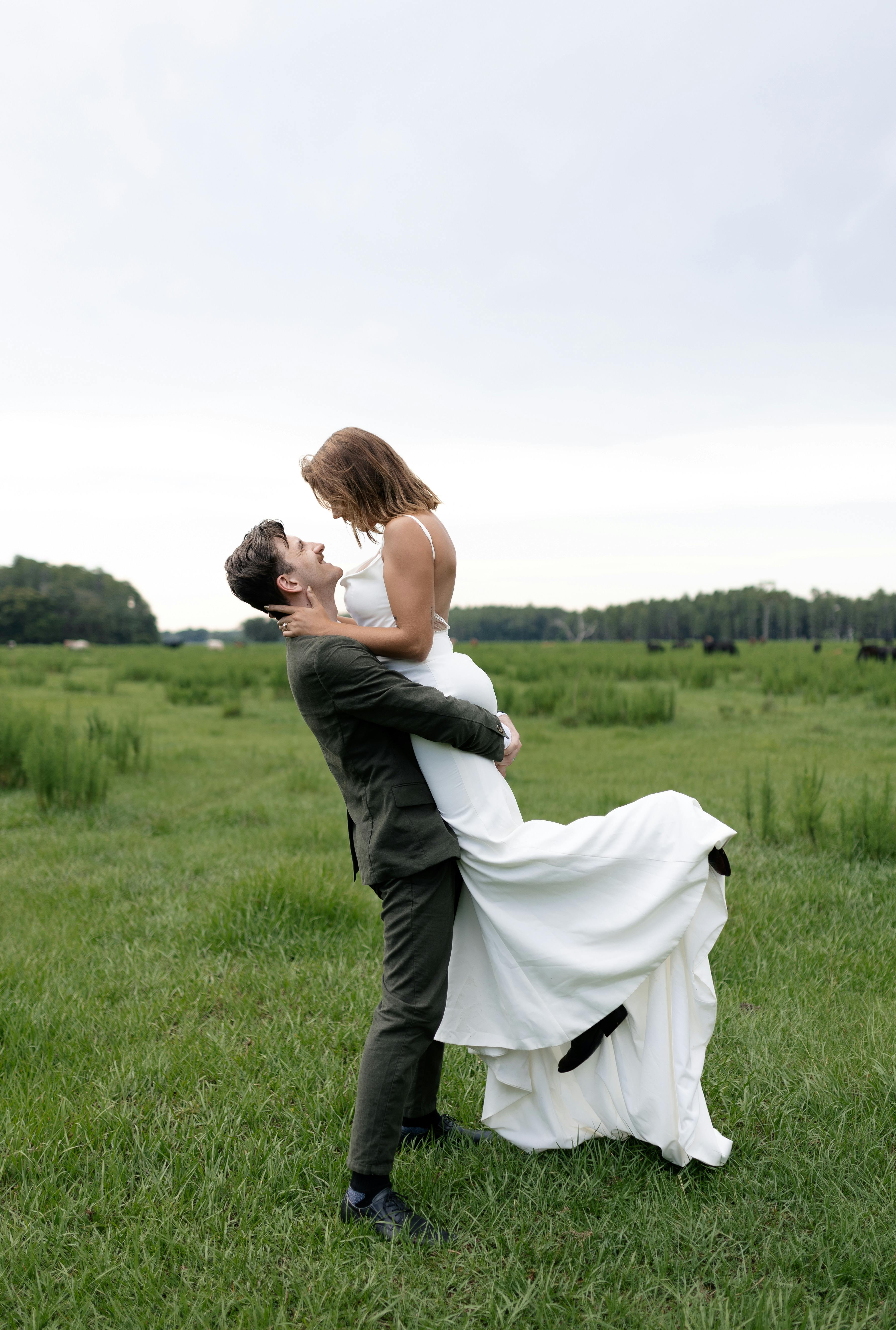 a bride and groom are standing in a field