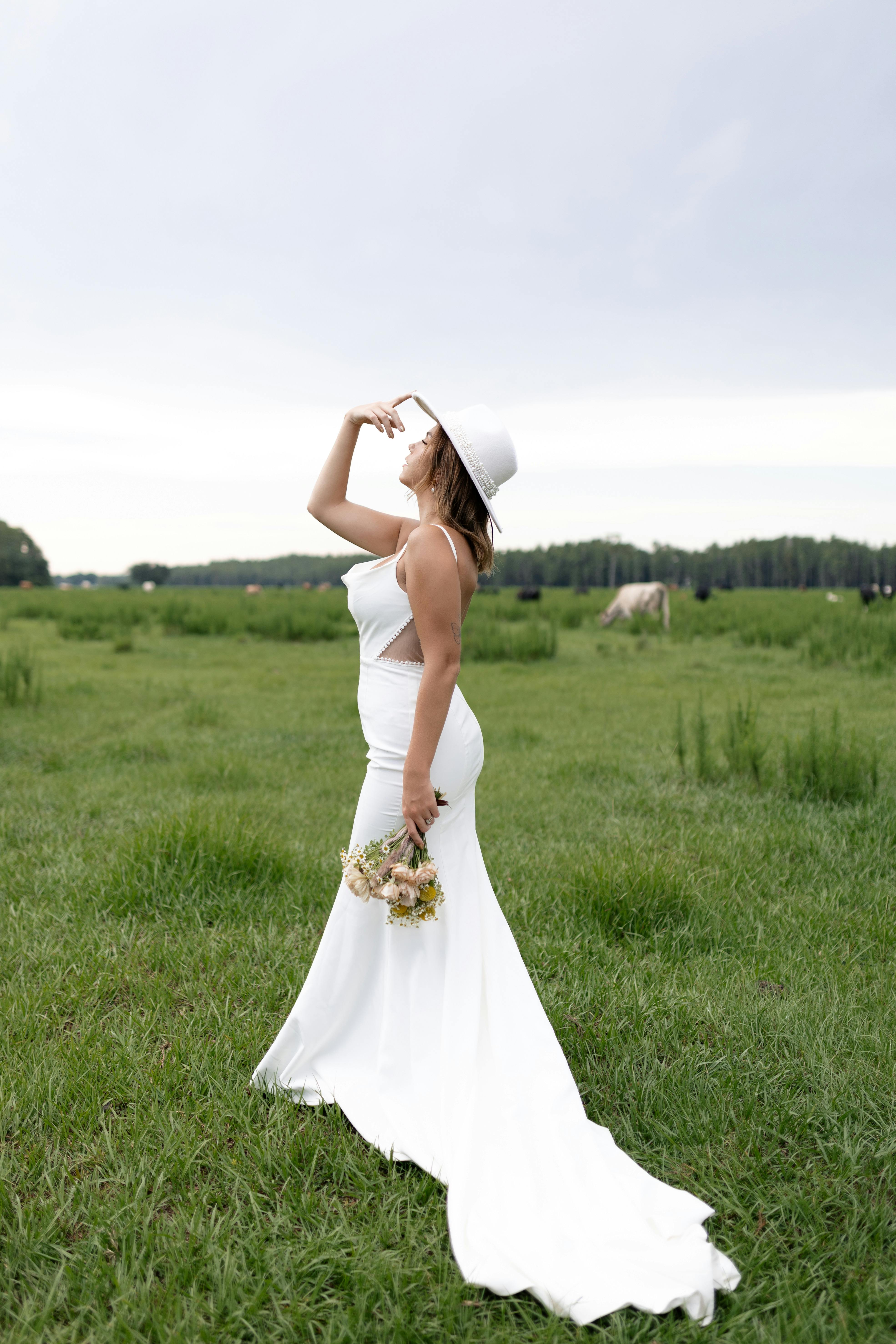 a bride in a white dress standing in a field