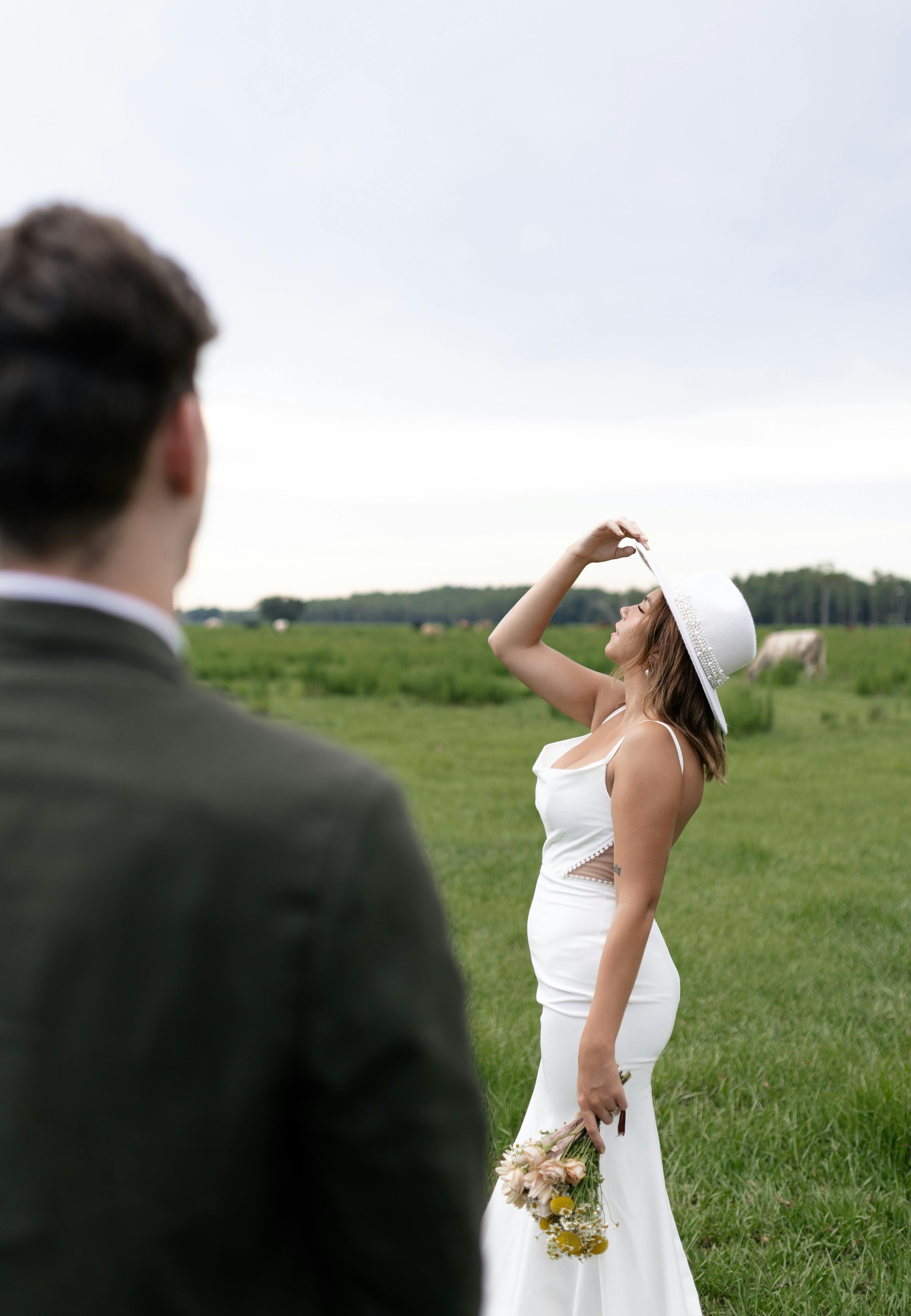 a bride and groom are standing in a field