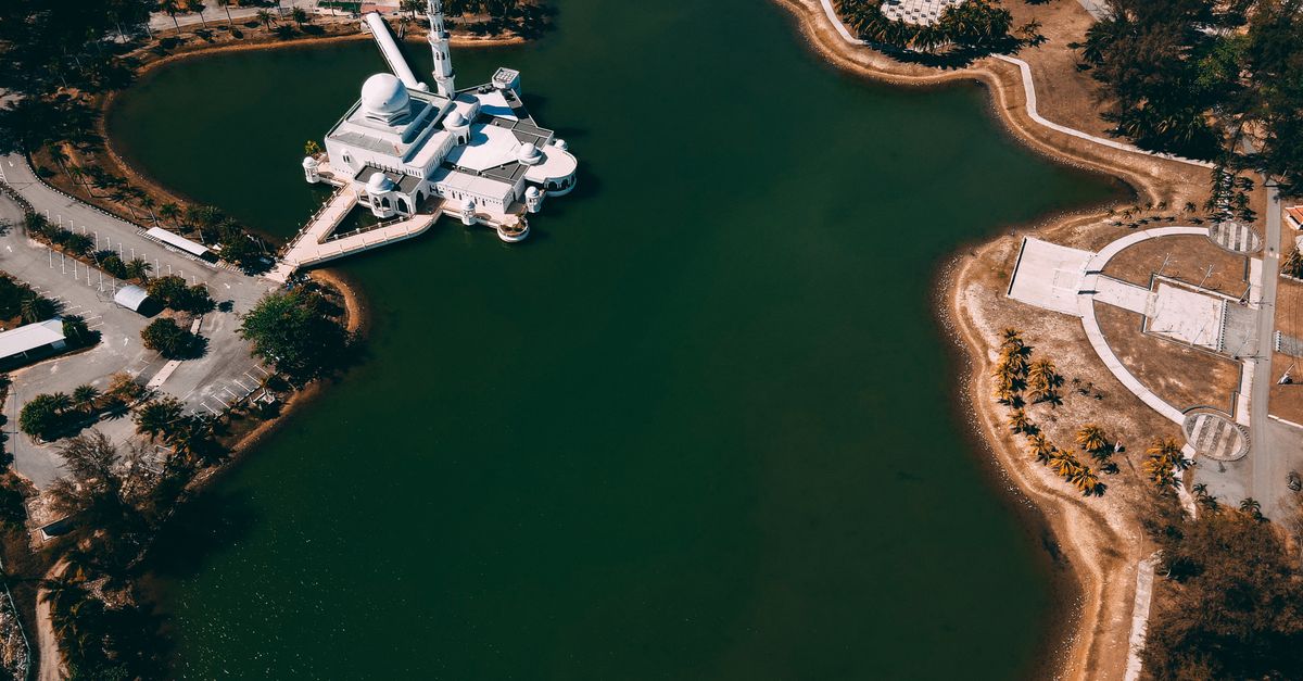Stunning aerial view of an isolated mosque on a tranquil lake island with surrounding landscape.