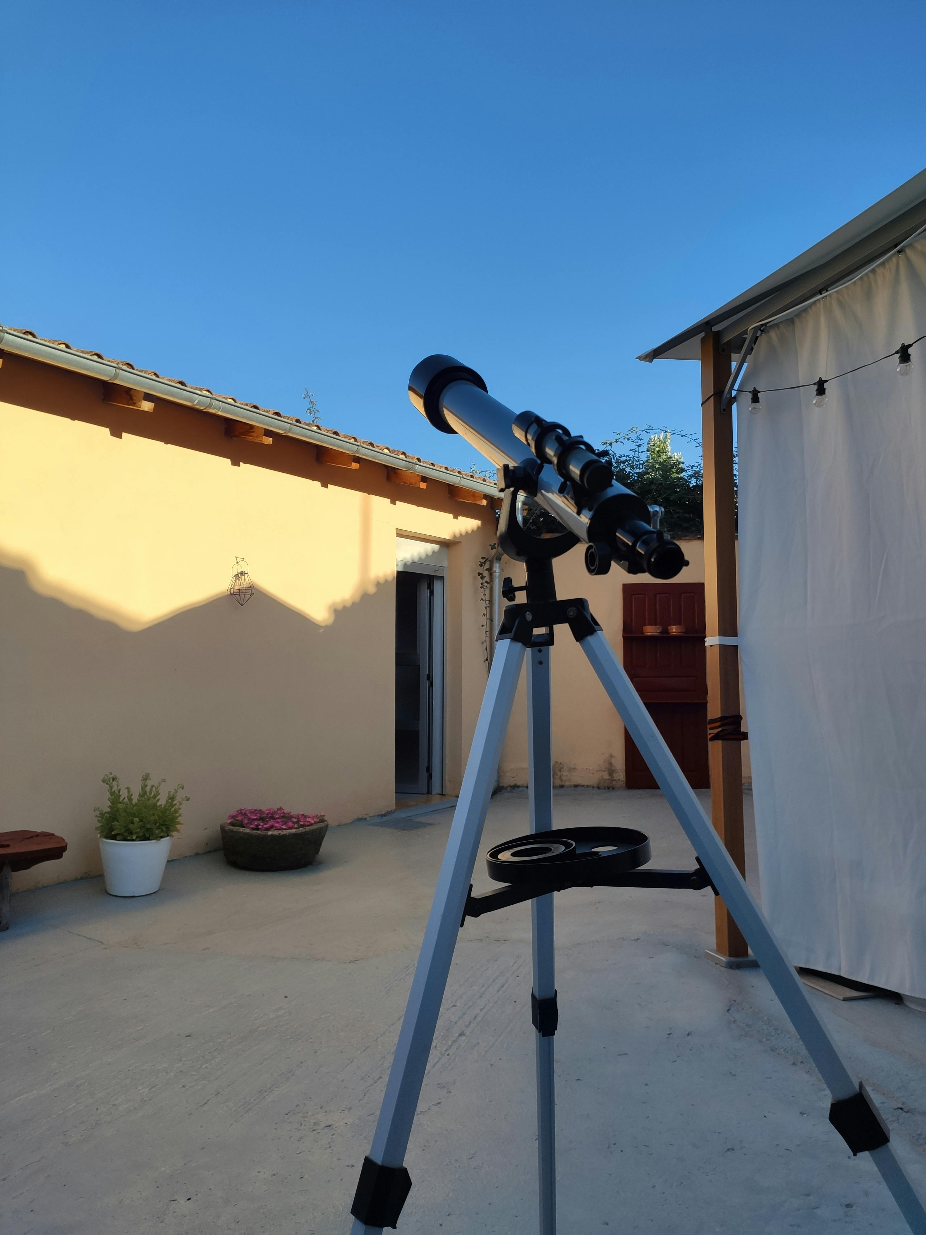 petit telescope sur son trepied installe dans un petit jardin a cote d une tente d observation en plein jour pret a observer les etoiles avant la nuit