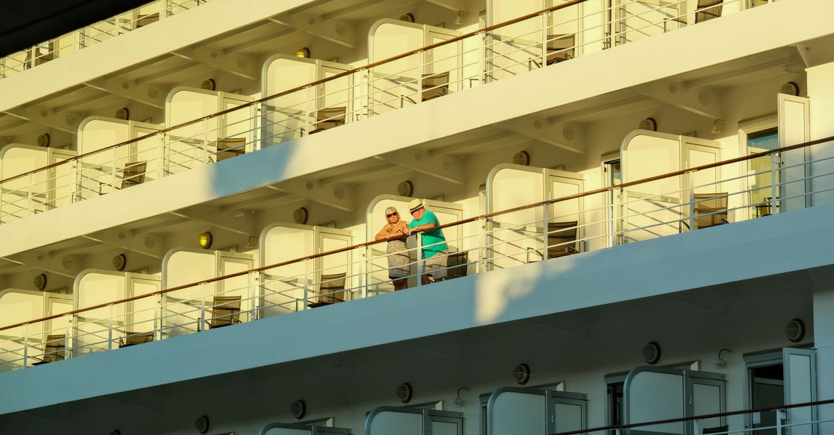 Two adults enjoying a sunny day on a cruise ship balcony.