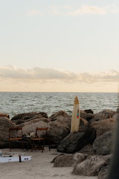 A picturesque scene of a surfboard on rocks at St. Pete Beach, Florida, during sunset.