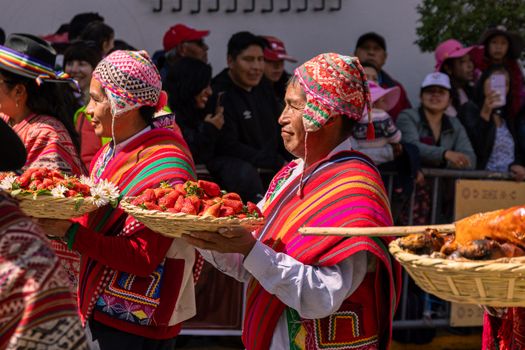A group of women in traditional clothing carrying baskets of fruit