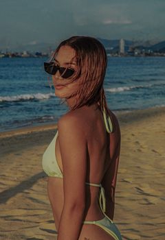 Woman in a bikini with sunglasses enjoying a sunny day on the beach. Perfect vacation scene.