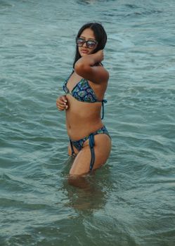 Young woman in a colorful bikini relaxing in the ocean, capturing the essence of summer fun.