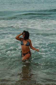 A woman in a bikini enjoying the ocean waves, embodying summer relaxation.