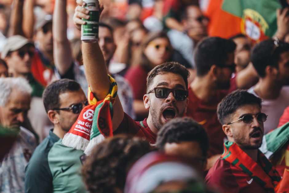 A lively crowd passionately cheering at a sports event, waving flags and enjoying the vibrant atmosphere.