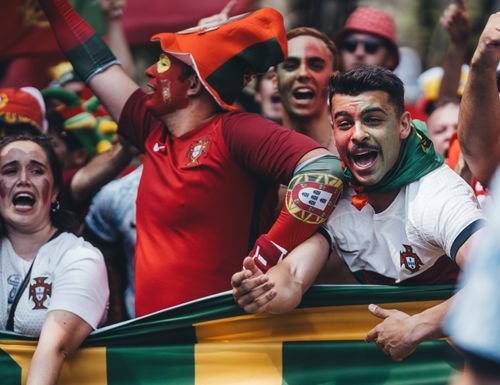 Free Passionate Portuguese soccer fans celebrating outdoors with flags and face paint. Stock Photo
