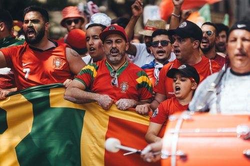 Free Group of diverse soccer fans cheering passionately, waving flags and celebrating in a vibrant parade. Stock Photo