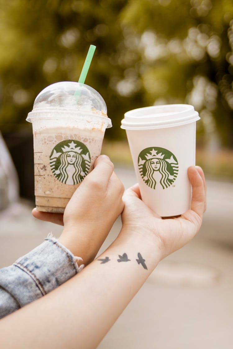 Persons Holding Starbucks Cups
