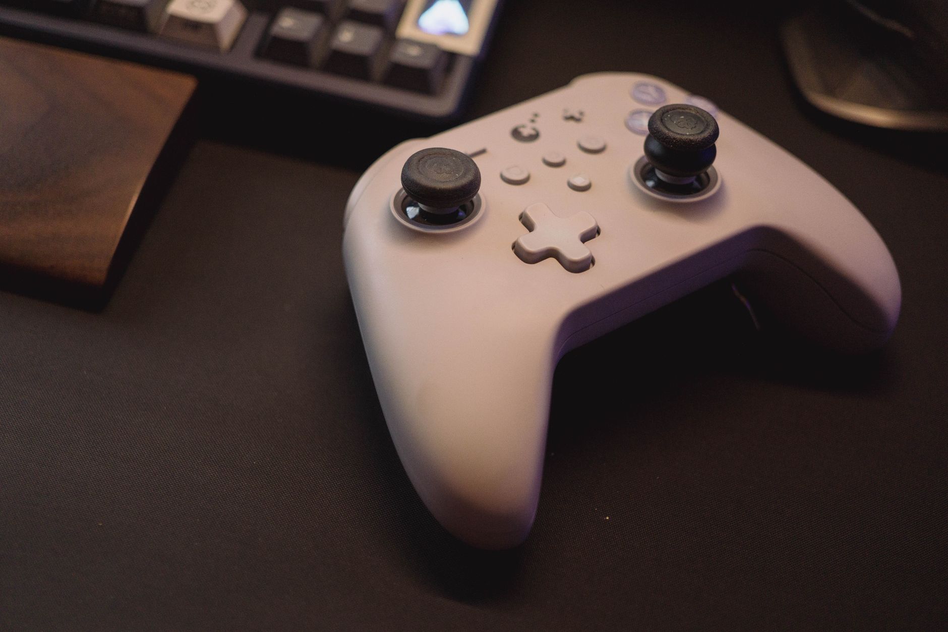White gaming controller on a black desk setup, symbolizing modern gaming.