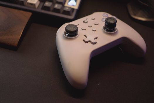 White gaming controller on a black desk setup, symbolizing modern gaming.