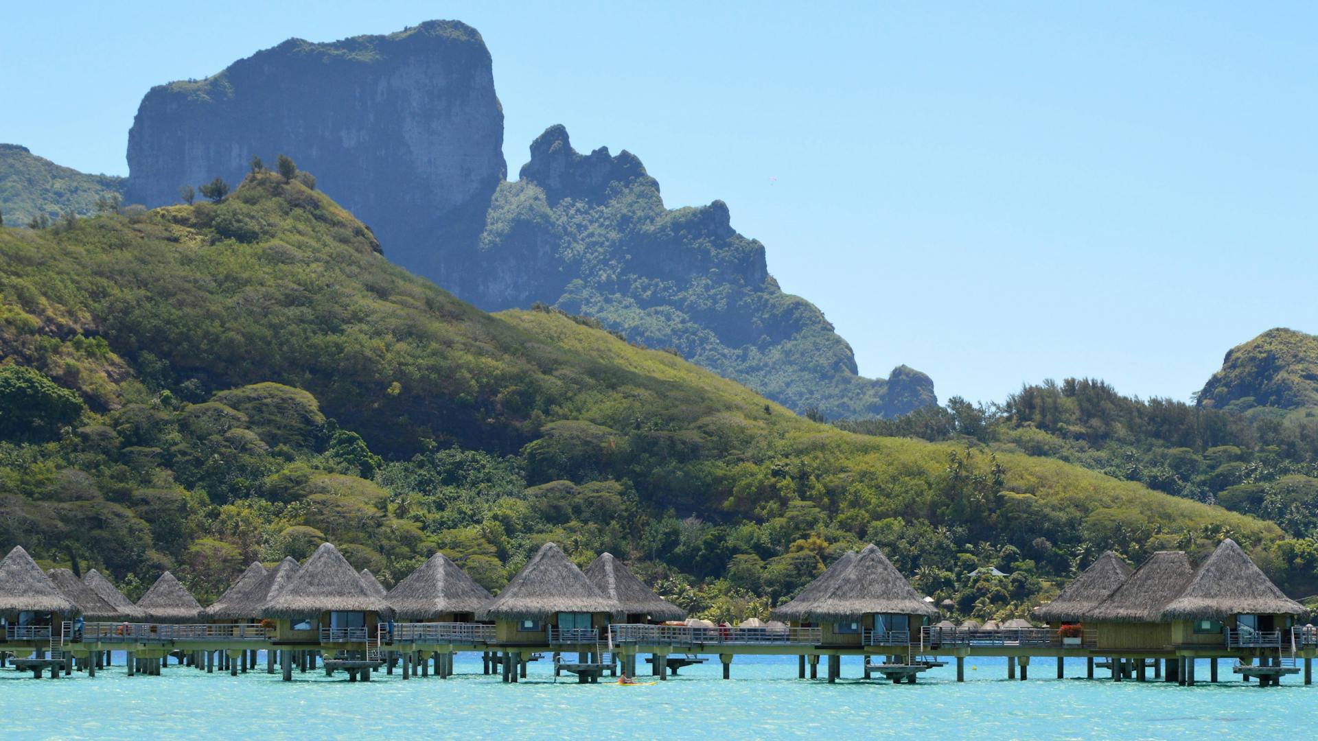 Scenic view of iconic overwater bungalows and lush hills in Bora Bora, French Polynesia.