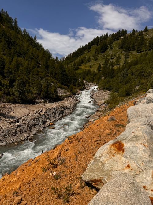 Free A picturesque river flows through a forested mountain valley under a clear blue sky. Stock Photo