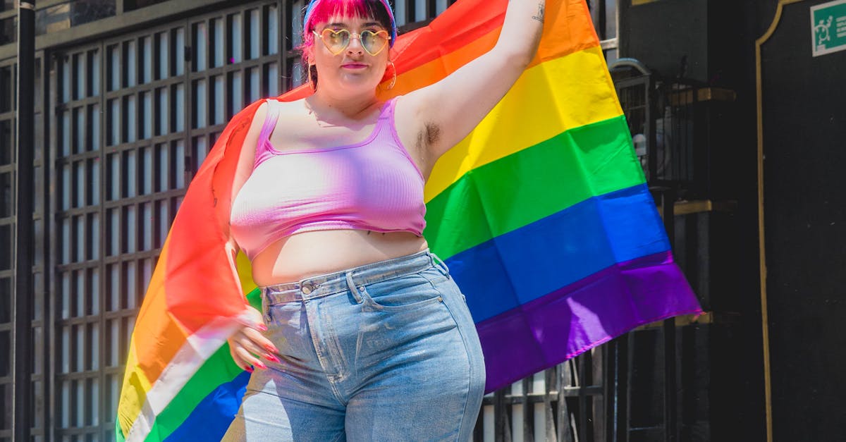 A woman in a pink top and jeans holding a rainbow flag