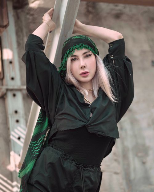 Free Stylish woman with a green headscarf and black outfit striking a pose outdoors. Stock Photo
