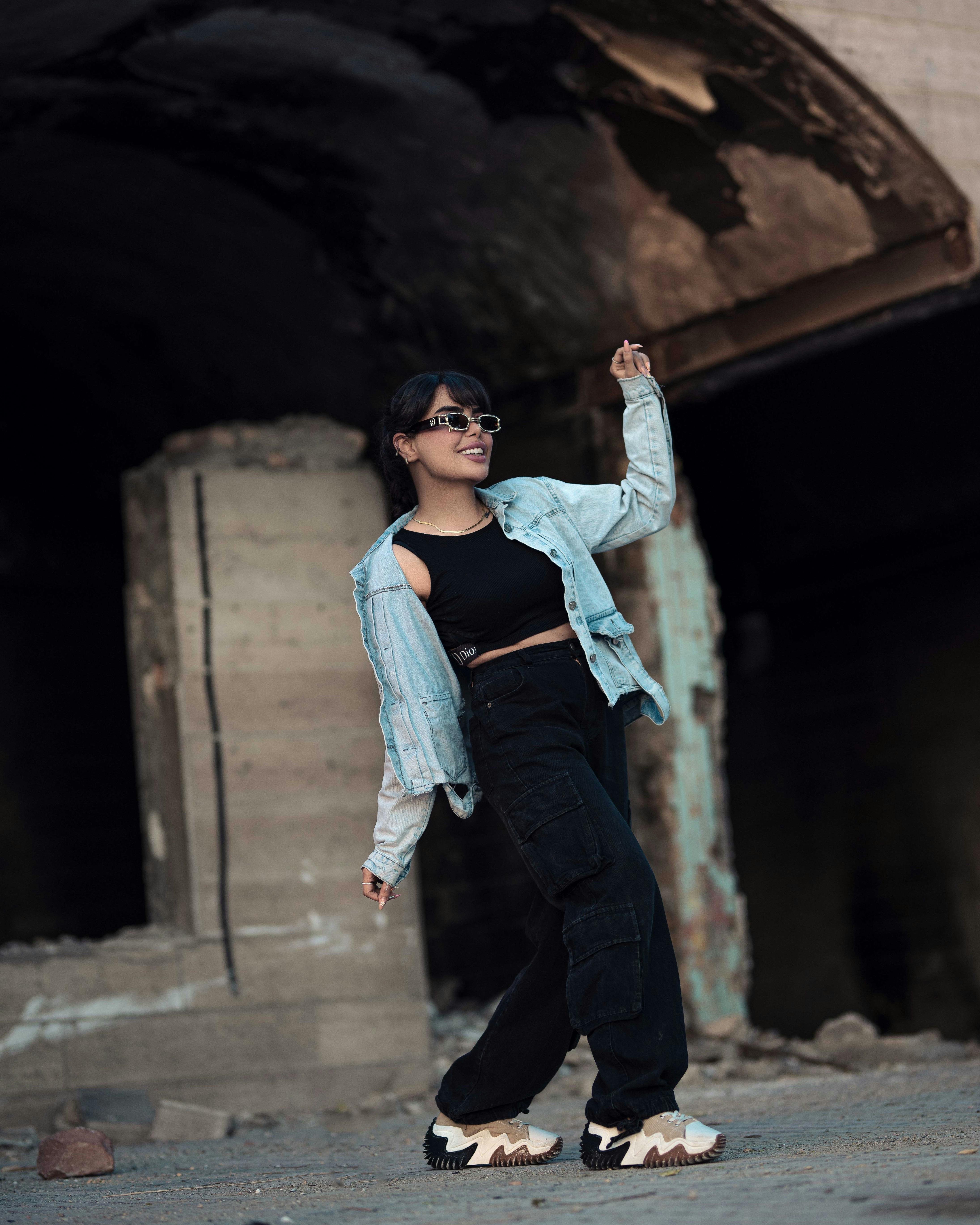 a woman in black pants and a jacket is standing in an abandoned building