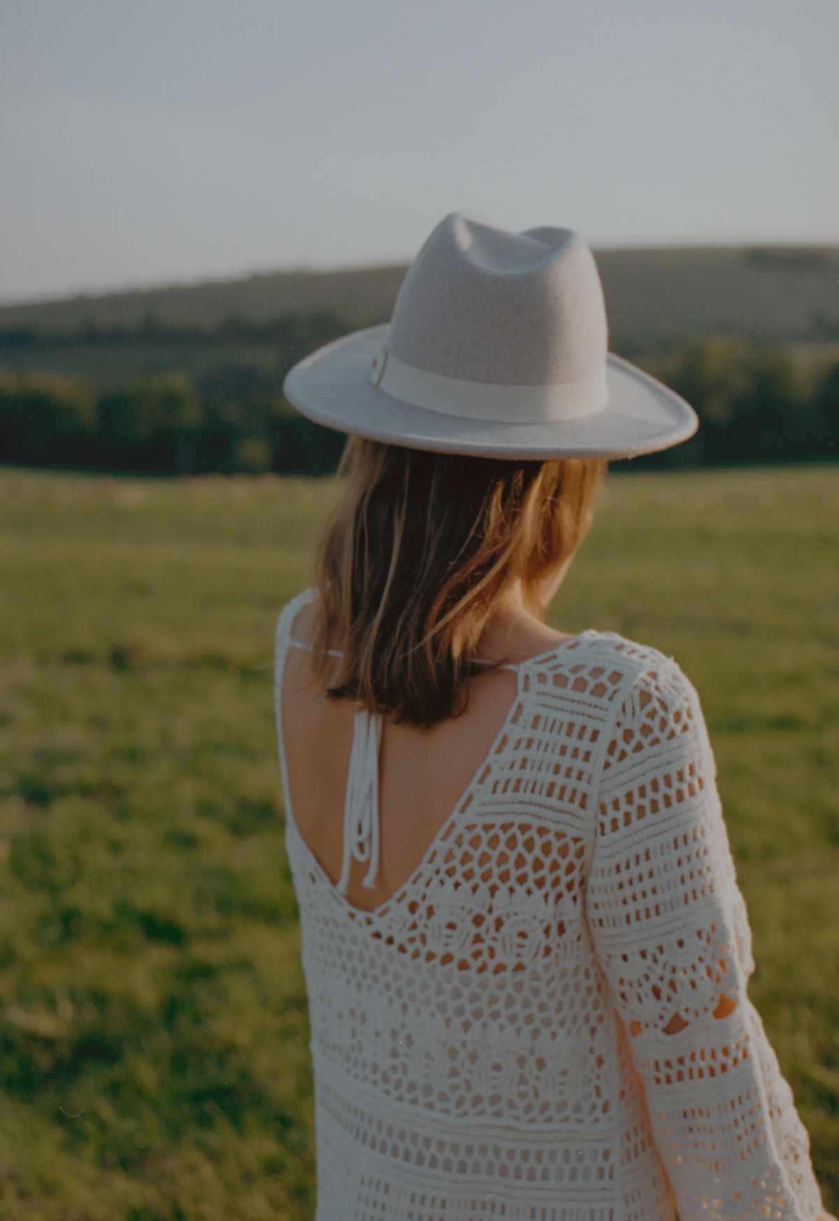 The back of a woman wearing a hat in a field — the holiday spirit of summer crochet