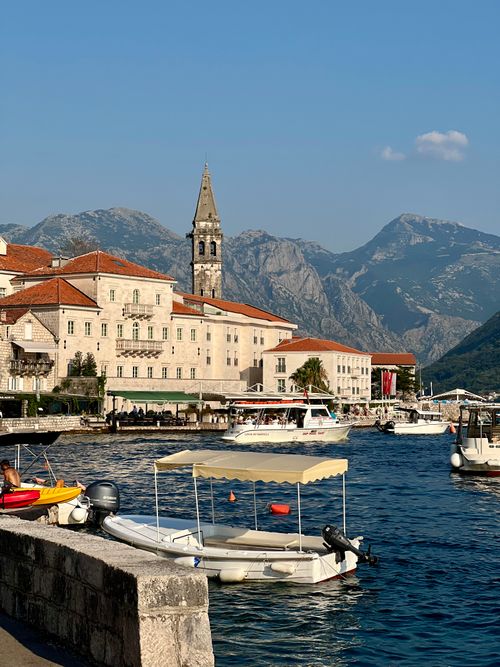 Free A scenic view of an Adriatic seaside town with boats, historic buildings, and mountains. Stock Photo