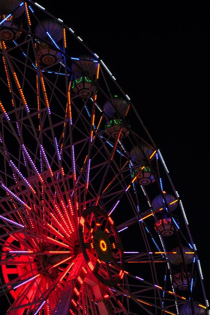 Illuminated ferris wheel glowing against a dark night sky, showcasing vibrant carnival lights.