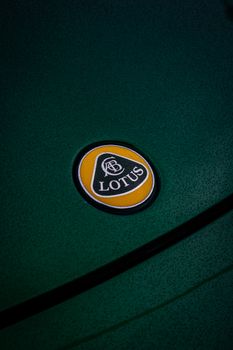 Detailed shot of a Lotus car badge on a textured green surface, showcasing elegance and luxury. 27274714