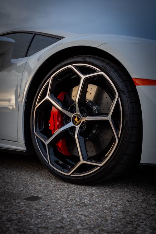 Free Detailed shot of a luxury sports car wheel featuring a red brake caliper and sleek rim design. Stock Photo