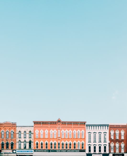 Vivid storefronts in a quaint small town against a clear blue sky creating a minimalistic vibe.