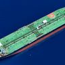 An aerial view of a massive green oil tanker navigating through deep blue ocean waters.