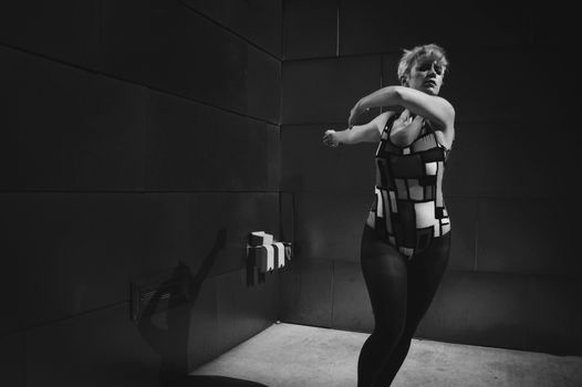A black and white portrait of a woman dancing gracefully in a studio setting, capturing elegance and motion.