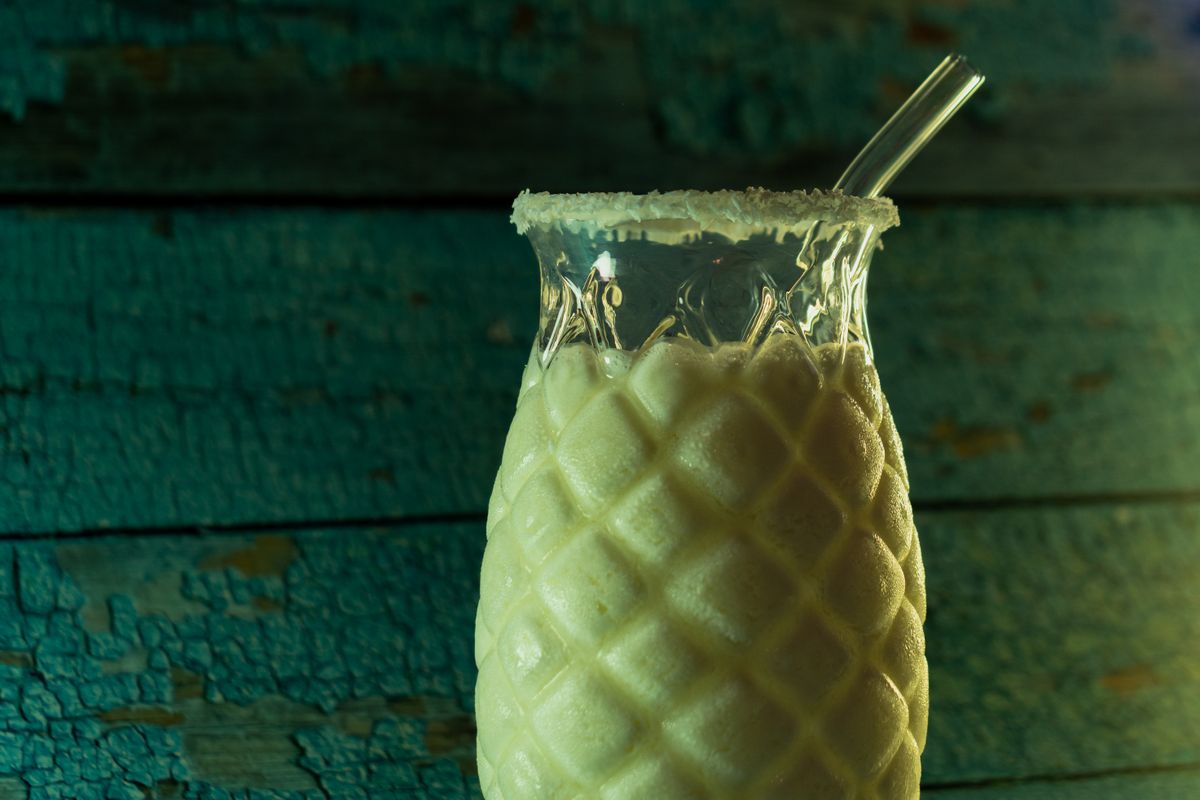 Chilled pineapple drink served in a textured glass against a rustic backdrop.