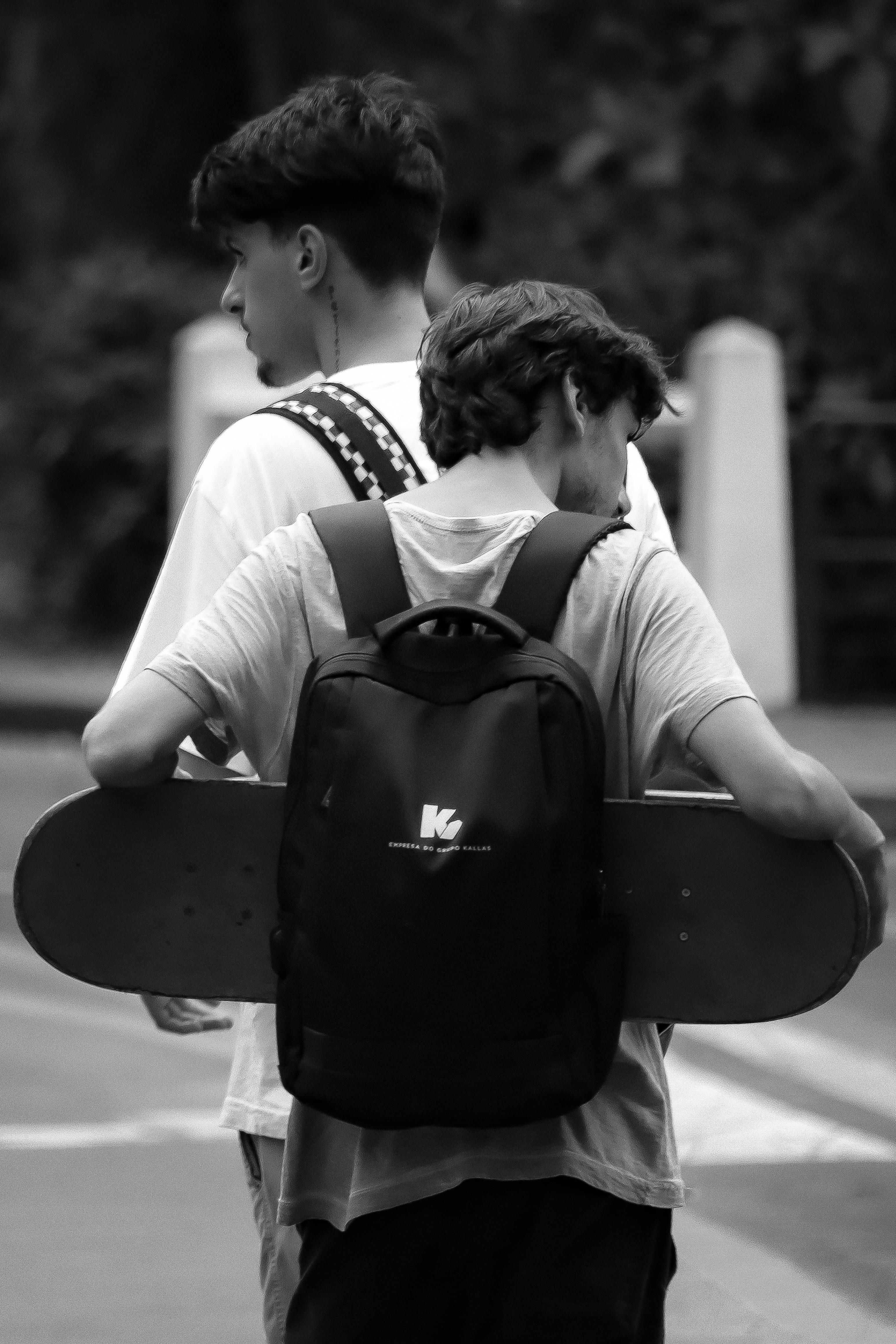 two young men with skateboards walking down the street