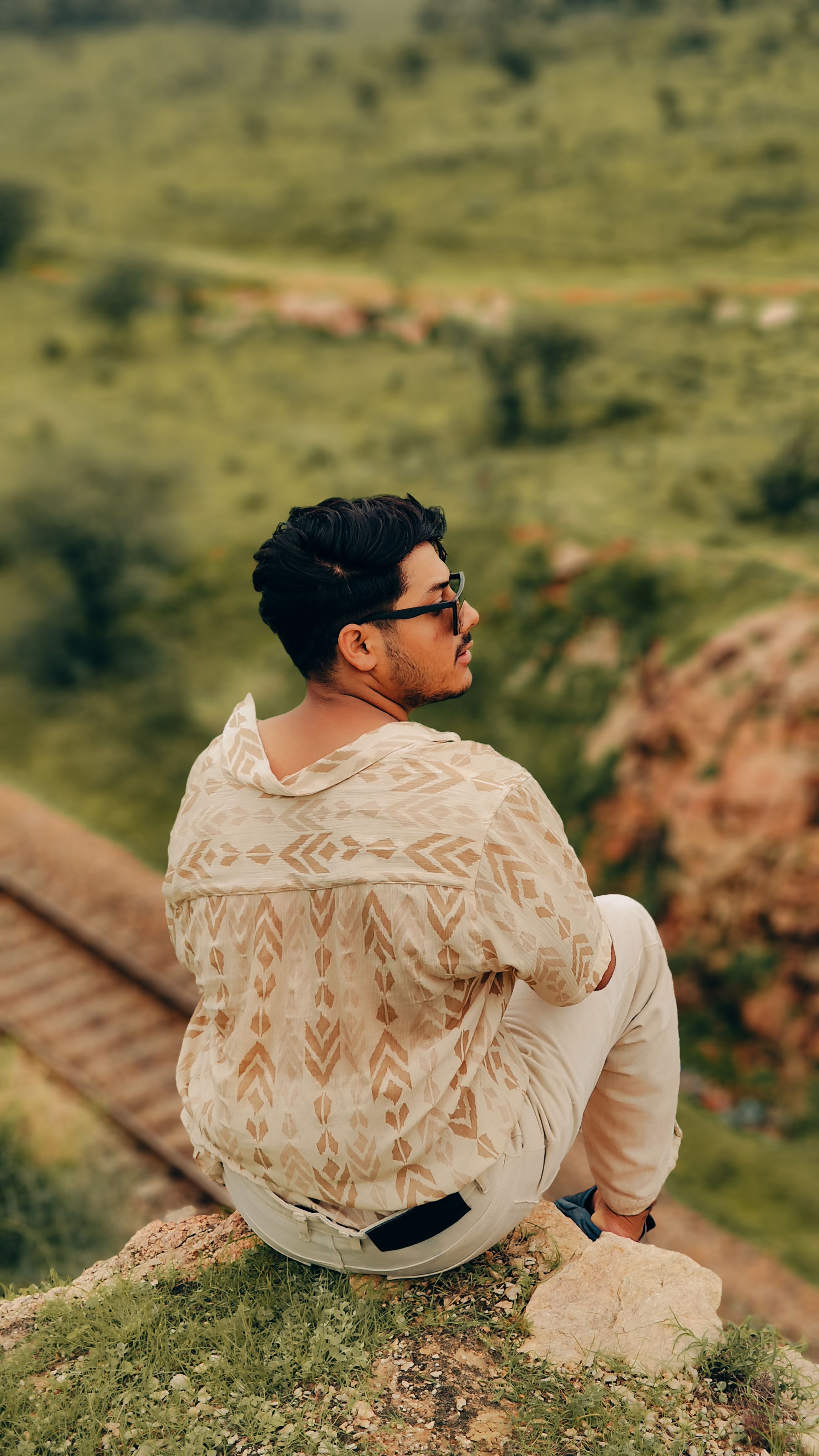 A young man sitting on a rock enjoying the Jaipur landscape, embodying leisure and relaxation.