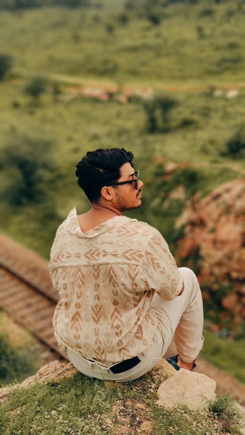 Free A young man sitting on a rock enjoying the Jaipur landscape, embodying leisure and relaxation. Stock Photo