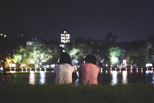 Couple Sitting on Grass in Front of Body of Water