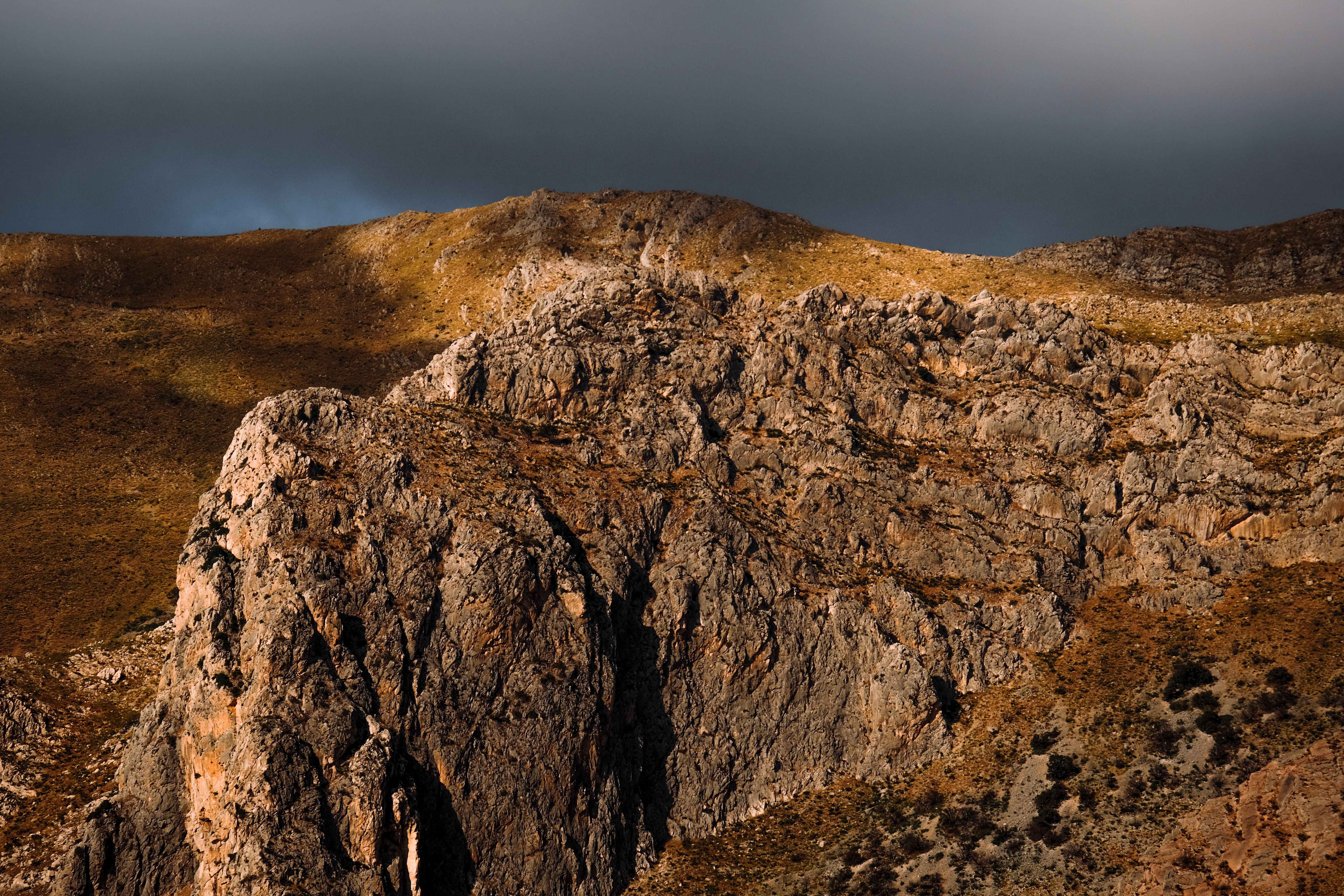 A mountain with a rocky cliff and a cloudy sky, Libya