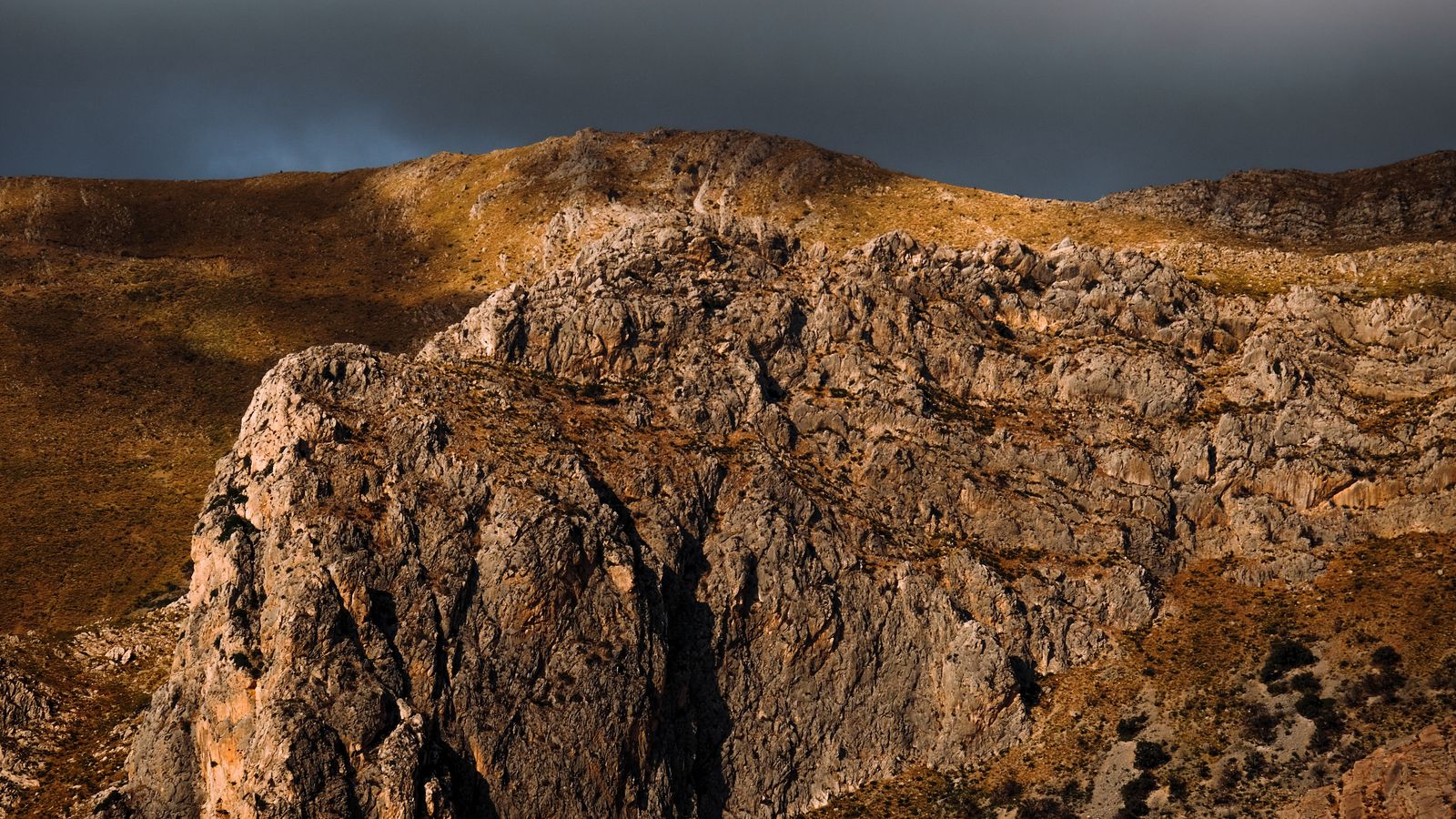 A mountain with a rocky cliff and a cloudy sky, Libya