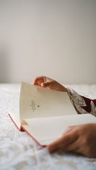 Close-up of hands turning pages of a book indoors on a cozy day.