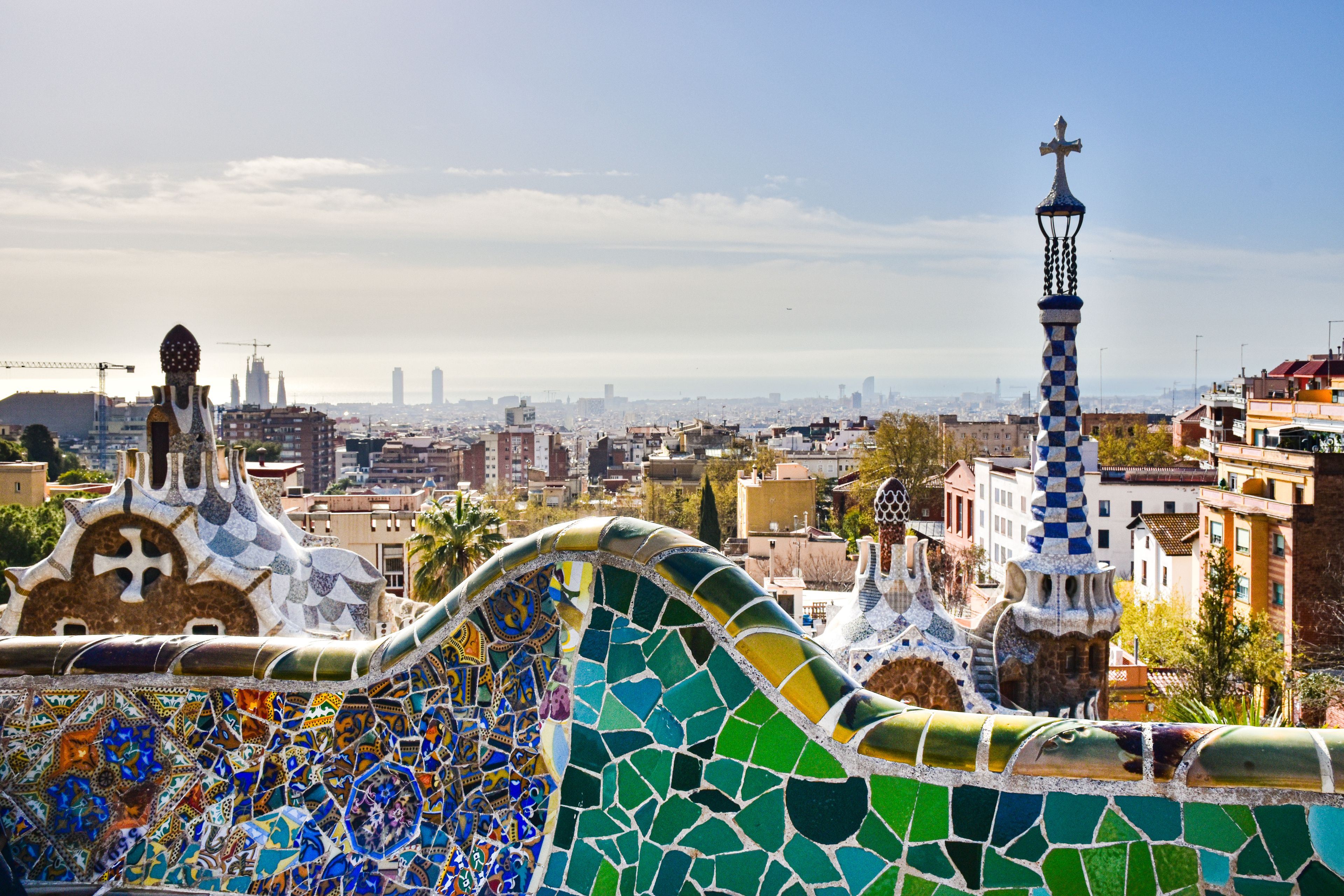 View of Barcelona from Park Güell showcasing mosaic architecture and city skyline.