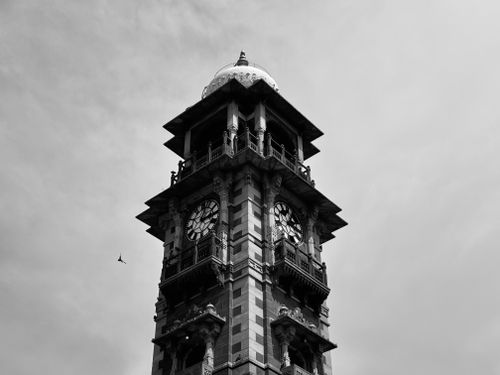 Free Black and white photograph of a historic gothic clock tower reaching into a cloudy sky. Stock Photo