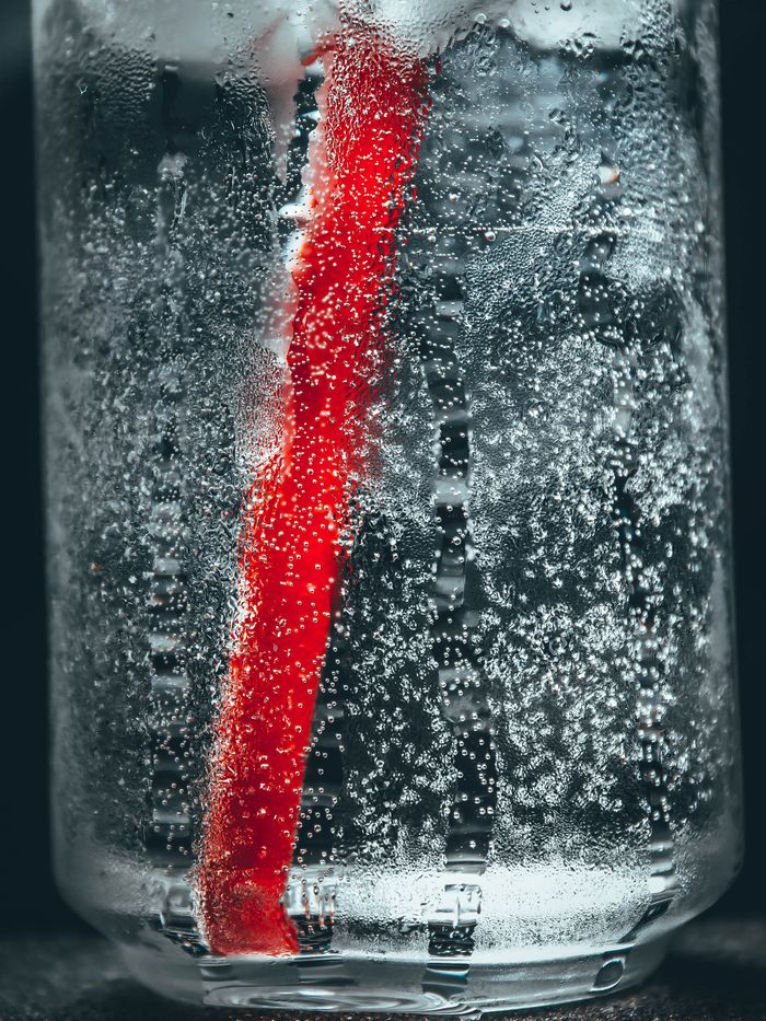 Close-up of a glass of sparkling water full of bubbles with a red straw