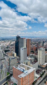 Aerial photo of a bustling city skyline with modern skyscrapers under a blue sky.