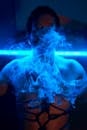 霓虹灯下，蓝色烟雾笼罩着一个人，营造出一种神秘而梦幻的氛围