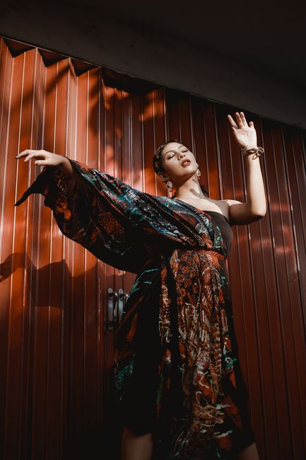 Beautiful Asian woman posing elegantly in a colorful dress. Captured with dramatic lighting and vibrant style.