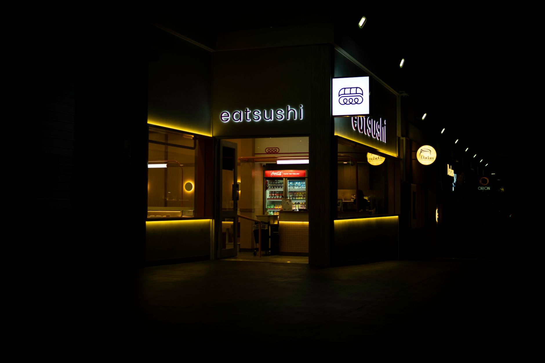 Night view of a warmly illuminated sushi restaurant entrance in Springfield, QLD, Australia.
