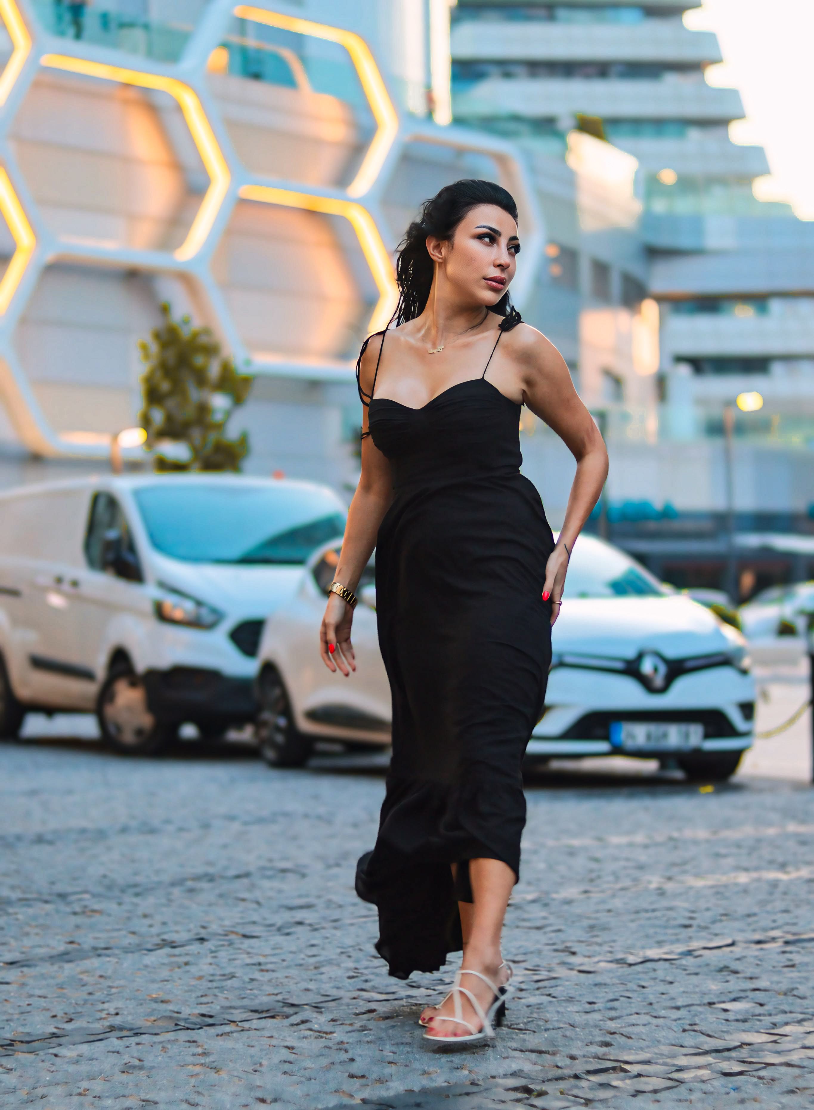 A woman in a black dress walking on a street · Free Stock Photo