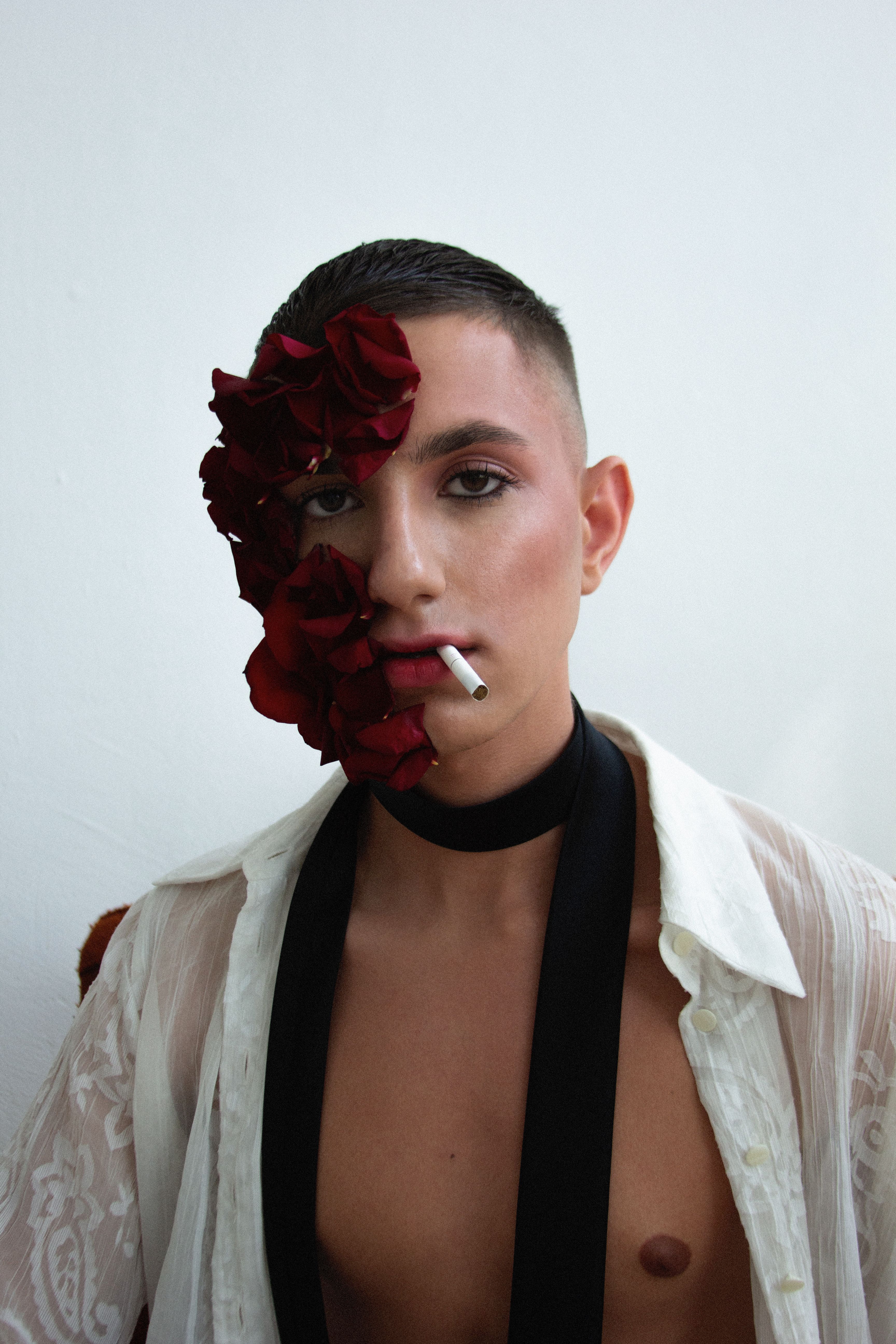 Modern portrait of a young man with floral elements, showcasing unique fashion style, taken in a studio setting.